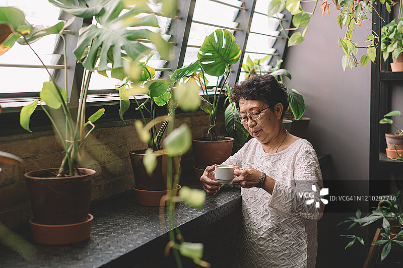 一位活跃的亚洲华裔年长女性正在办公室休息室喝咖啡休息图片素材