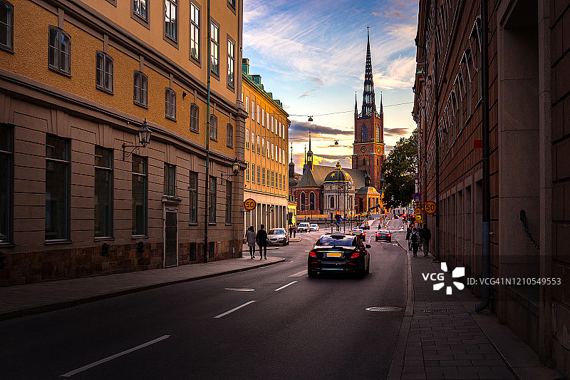 老城区里的Riddarholmen church背后的日落景观，斯德哥尔摩市的著名地标，游客和出租车在斯德哥尔摩市的道路上，瑞典，欧洲，斯堪的纳维亚半岛图片素材