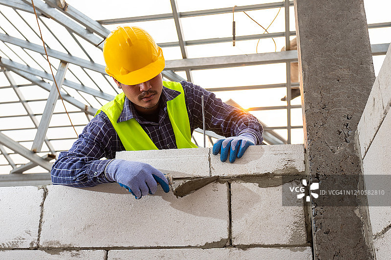砌砖工人使用蒸压加气混凝土砌块。筑墙，在建筑现场安装砖块，工程和建筑概念。图片素材