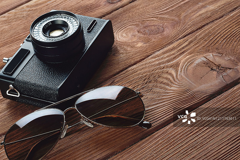 暑假必备物品:照相机、太阳镜。木制背景下的旅行配件。一名街头摄影师的旅游布局集。图片素材