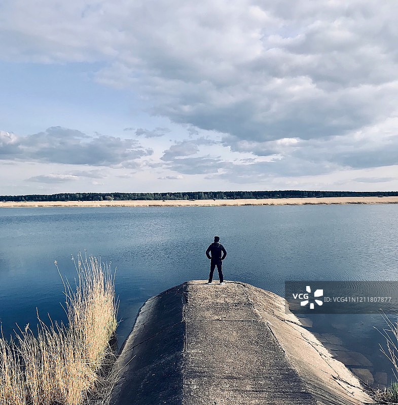 在拉脱维亚，一个男人站在河边图片素材
