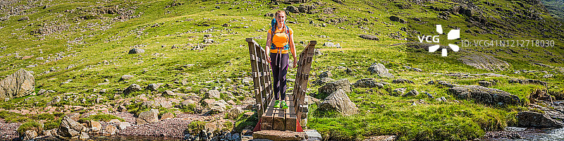 年轻的女登山家徒步穿越山涧桥小道全景图片素材