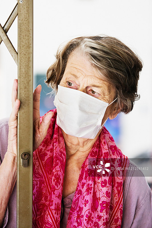 在COVID-19冠状病毒疫情期间，戴口罩避免感染的老年妇女图片素材