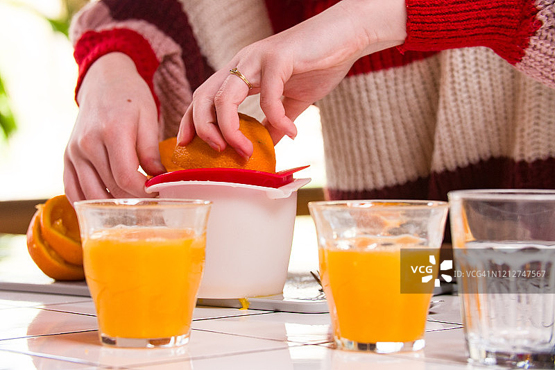 用榨汁机榨橘子汁。图片素材