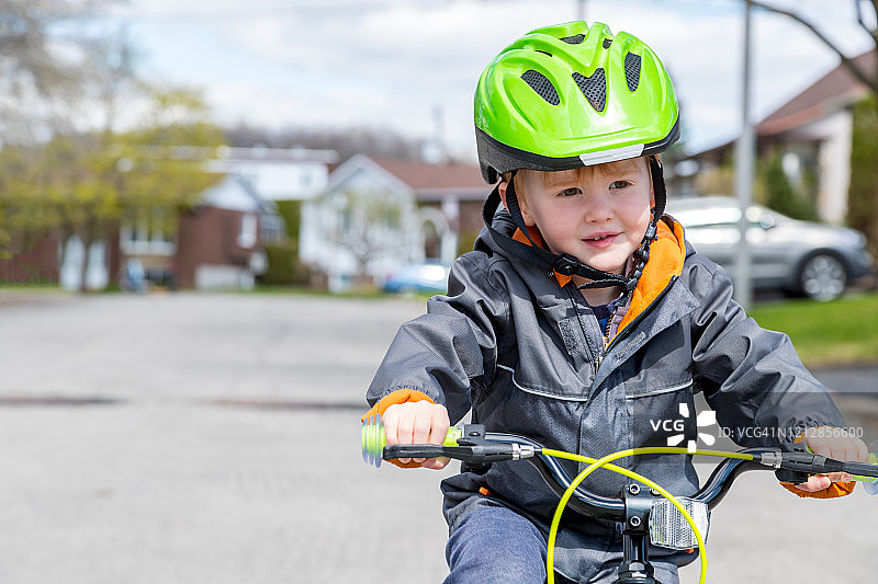小红发男孩骑着他的自行车在郊区的街道上，拉瓦尔，加拿大图片素材