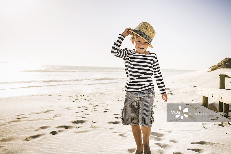 海滩上戴着帽子的微笑男孩的肖像图片素材