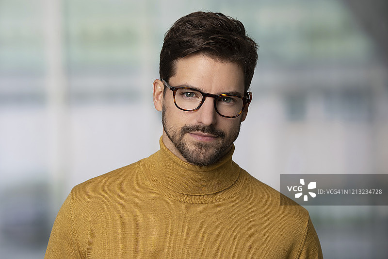 一个戴着眼镜，穿着黄色毛衣的自信男人的肖像图片素材