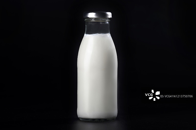 黑色背景上孤立的牛奶瓶。乳制品的食物。图片素材