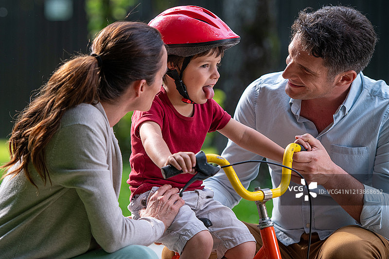 儿子学骑自行车时，父母跟他聊天图片素材