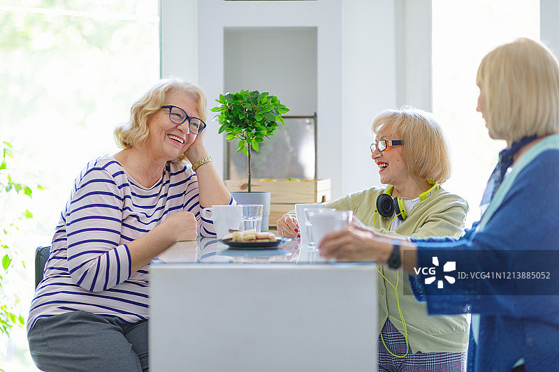 快乐的老女人在家边喝咖啡边聊天图片素材