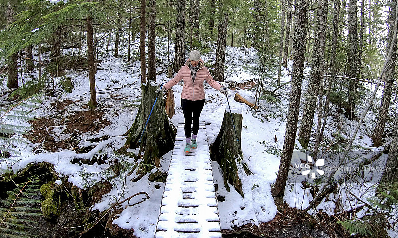女性徒步旅行者走过被雪覆盖的木板路图片素材