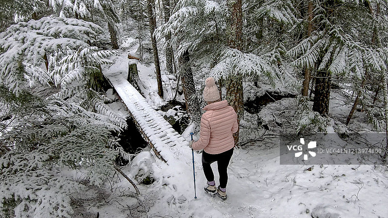 女性徒步旅行者接近积雪覆盖的木板路图片素材