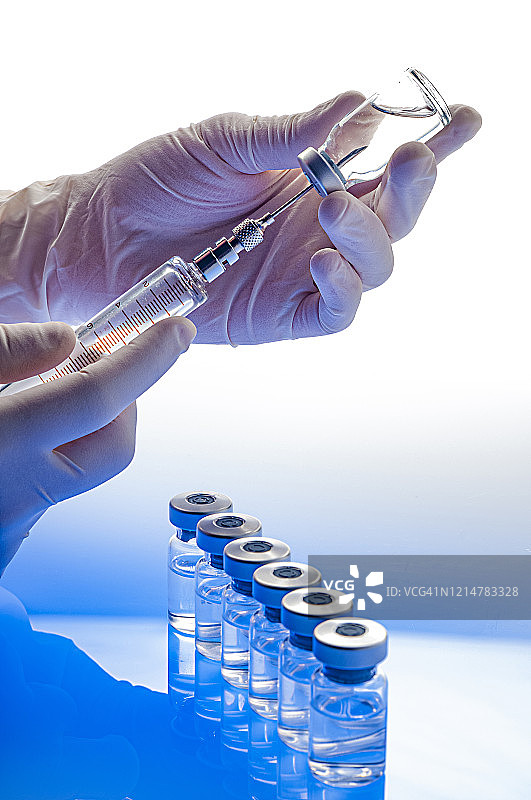准备疫苗:手持注射器和小瓶手套的手图片素材