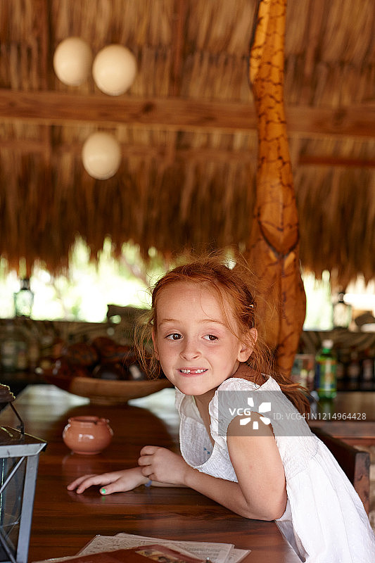 年轻女孩红头发坐在热带度假酒吧外看着远离镜头图片素材
