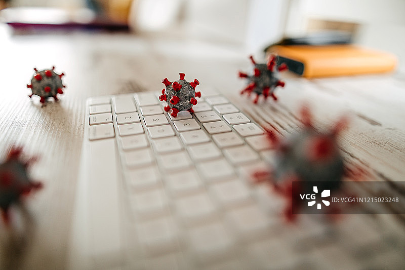 办公室桌上和键盘上的冠状病毒模型图片素材