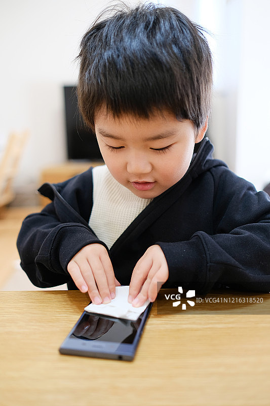 儿童擦拭智能手机，防止感染病毒图片素材