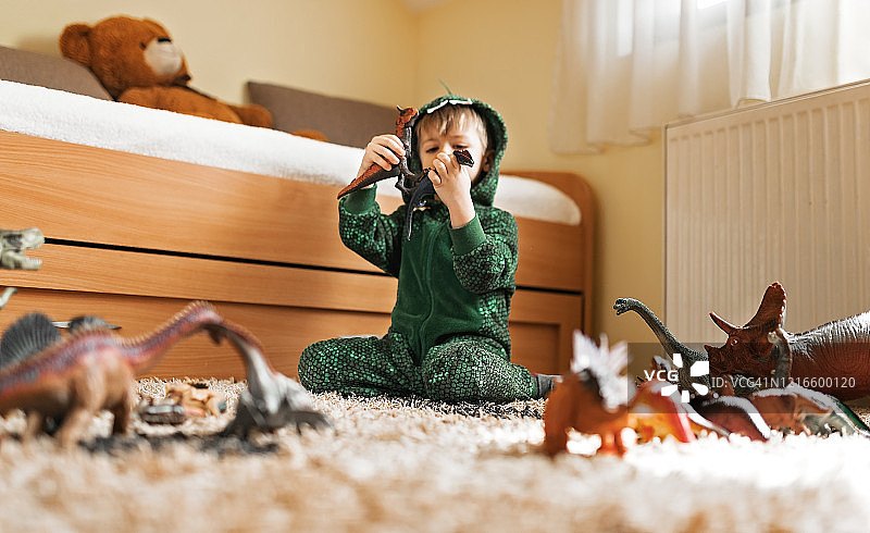 蹒跚学步的小男孩在玩他的恐龙图片素材