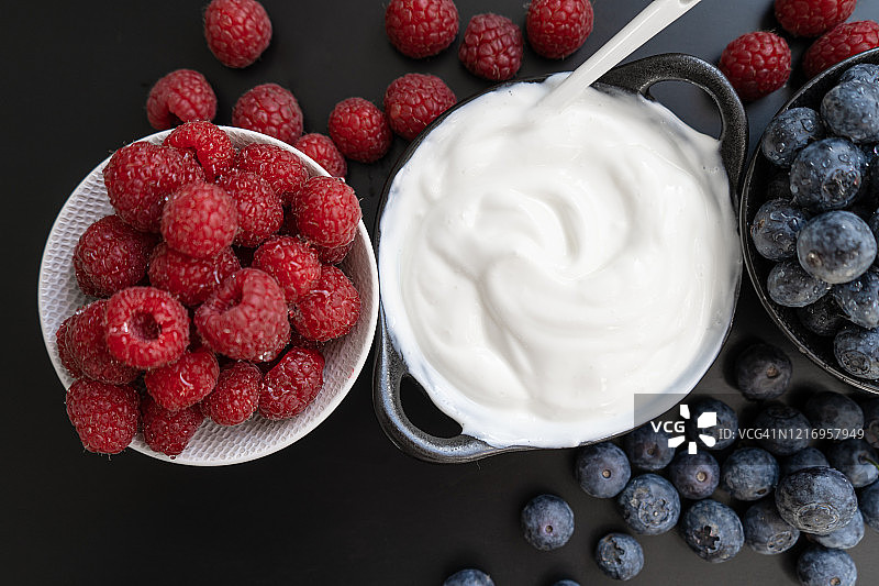 酸奶在碗和勺子，健康的早餐与新鲜的希腊酸奶，麦片和浆果的背景图片素材
