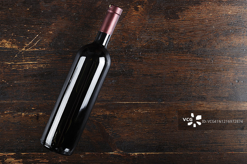 在一个棕色的木制背景上，一瓶封闭的葡萄酒。文本。图片素材