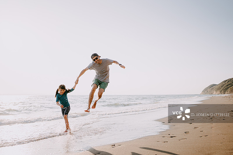 爸爸和孩子在沙滩上又跑又跳图片素材