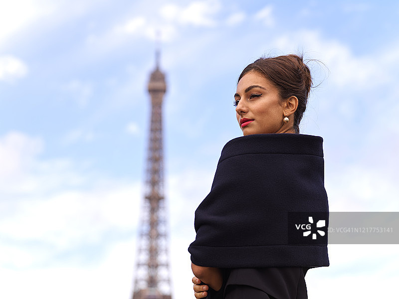 法国巴黎，白天，时髦的女人站在埃菲尔铁塔前图片素材
