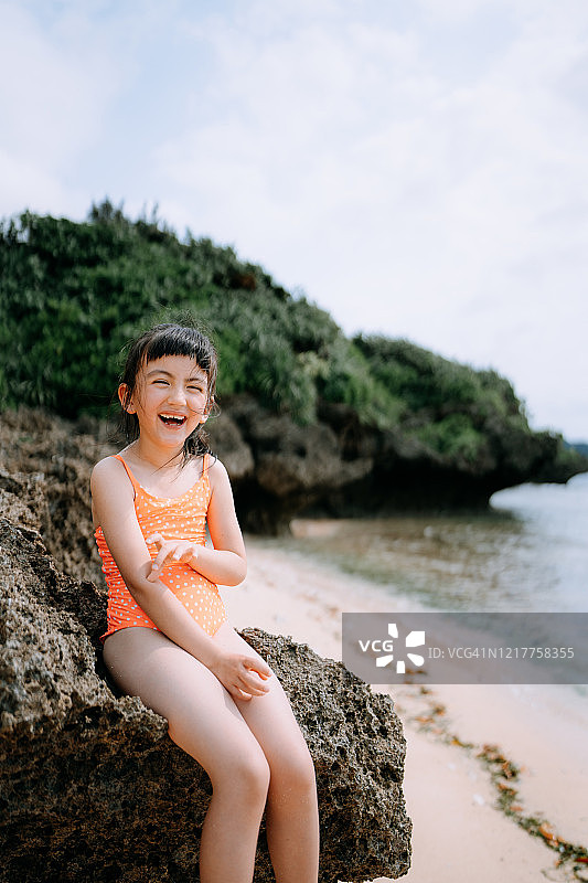 可爱的混血女孩对着照相机笑在海滩上，日本图片素材