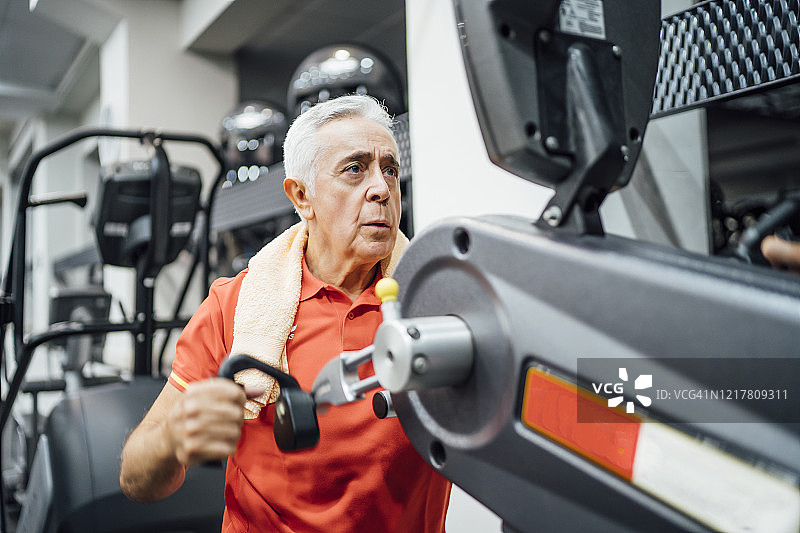 老年人在健身房的健身器上练习图片素材
