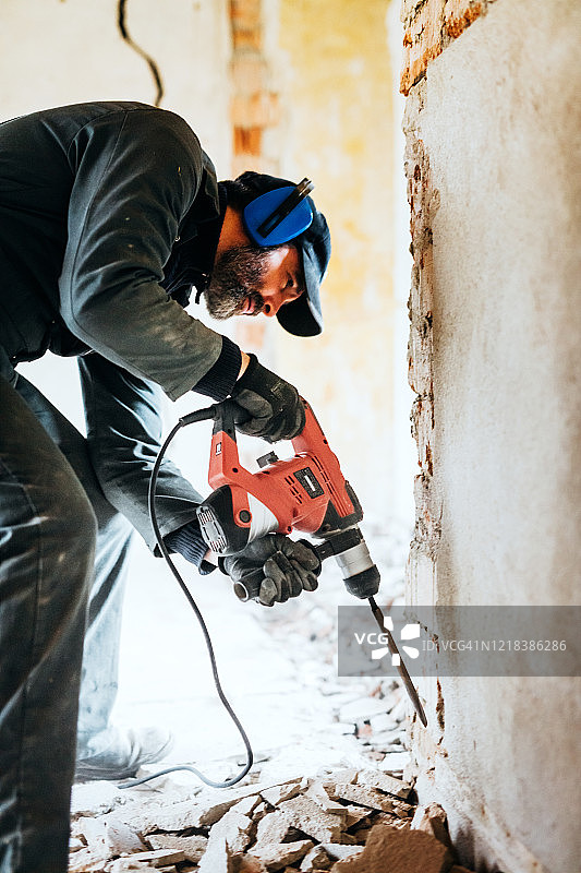 男工人用风动锤钻切割墙壁上的混凝土砖图片素材