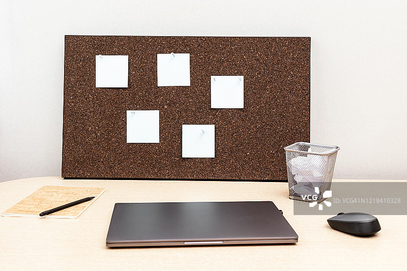 在家工作。工作用的笔记本电脑和贴着空纸条的木制公告板。自由职业者的工作空间。图片素材