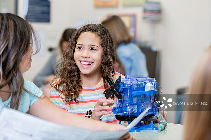 小学年龄的学生微笑在科学实验室，而工作在一个STEM项目的模型马达图片素材