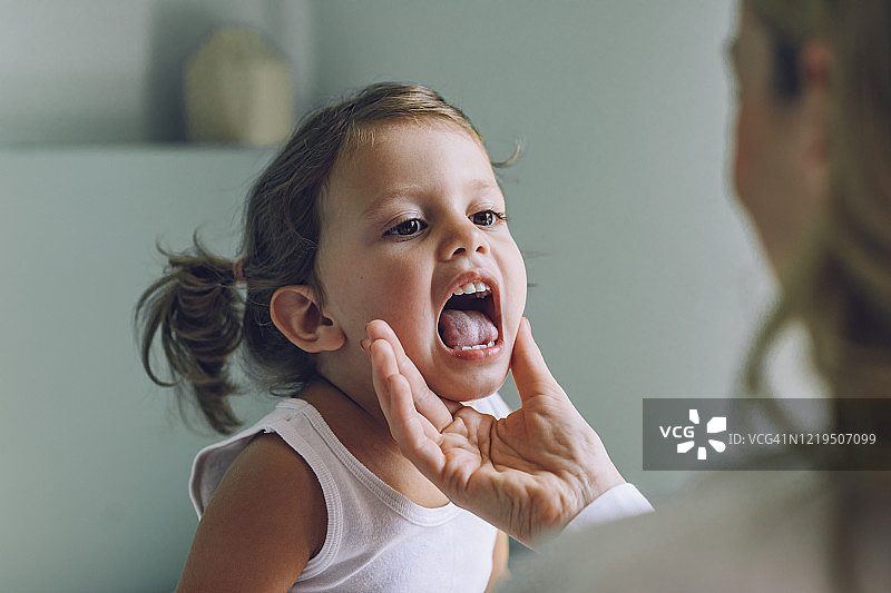 儿童在医学检查:儿科医生检查一个小女孩的喉咙图片素材