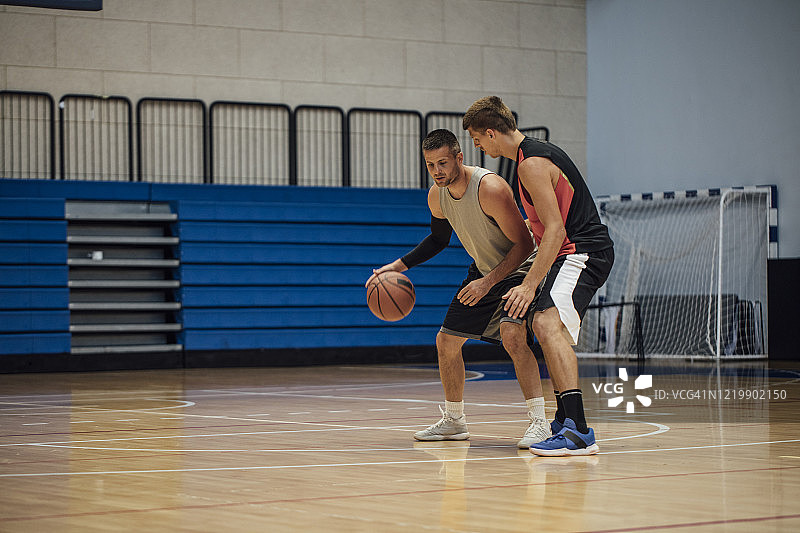 两名年轻运动员在学校体育馆打篮球图片素材