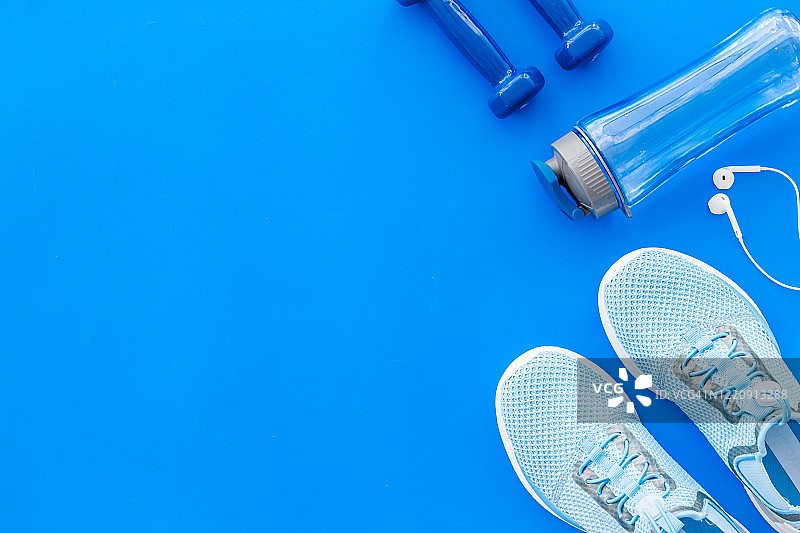健身配件。哑铃和运动鞋上的蓝色桌面视图拷贝空间图片素材