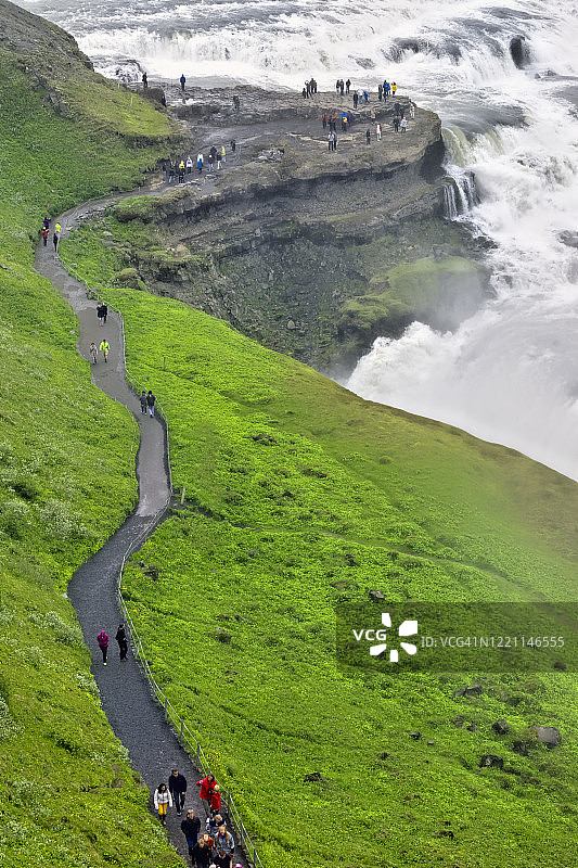 冰岛。游客接近金色瀑布图片素材