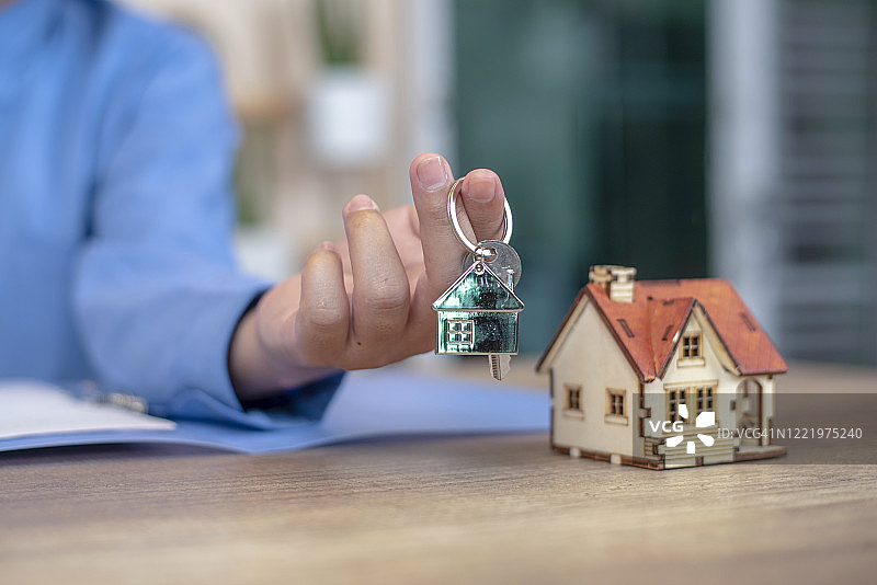 手握家钥匙链和房子模型。房地产投资和房屋抵押金融房地产图片素材