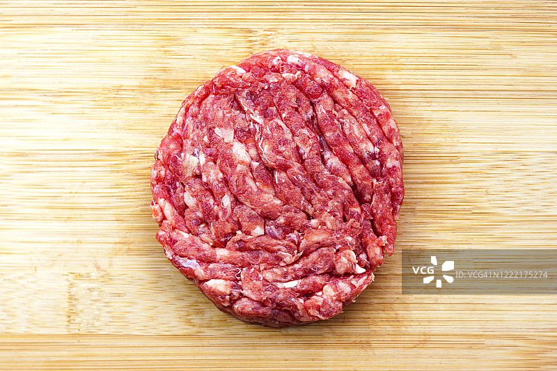 生牛肉汉堡烹饪在天然竹木砧板背景特写。前视图。图片素材