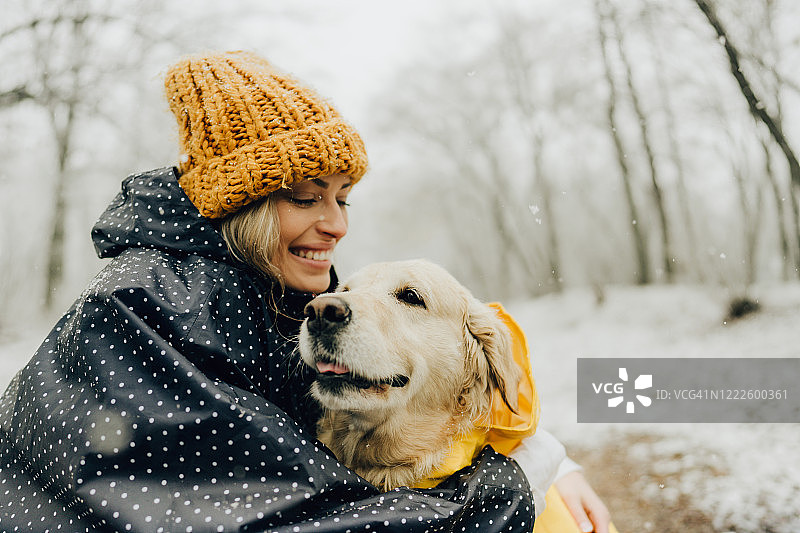 微笑的女人和她的狗在一个下雪天图片素材