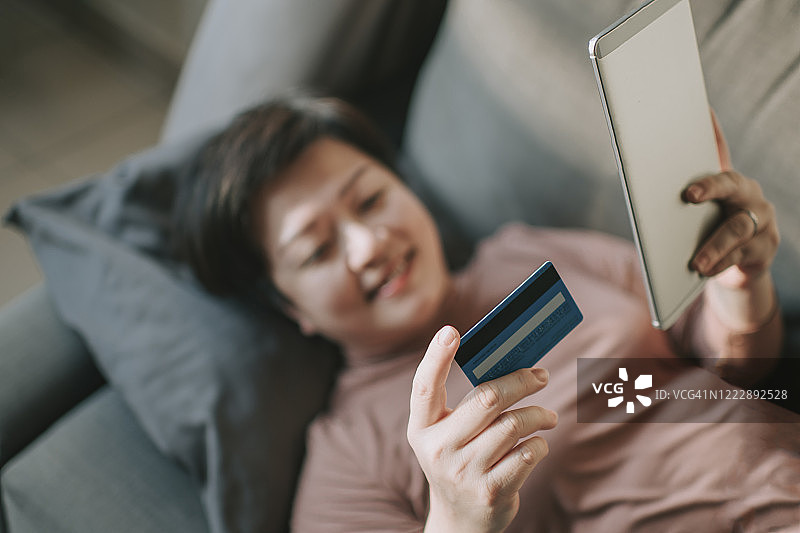 一位亚洲华人中年妇女用她的笔记本电脑和信用卡在网上购物图片素材