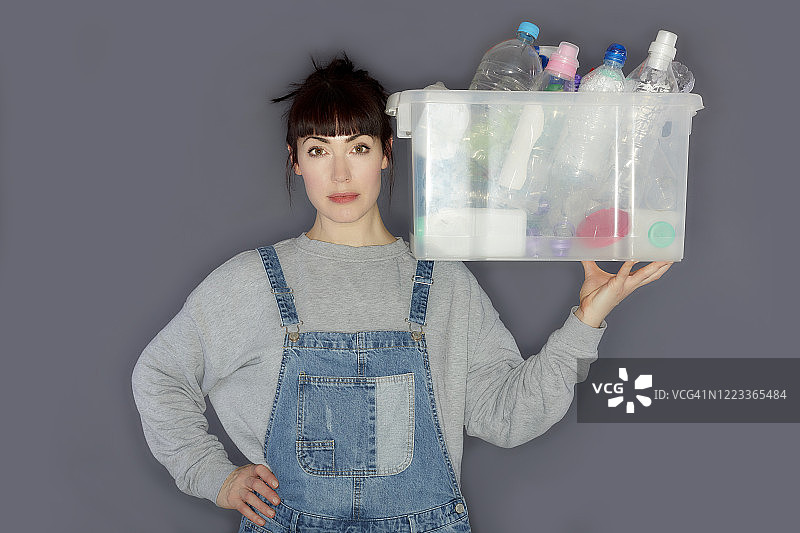 年轻女子拿着一个装有塑料瓶的盒子供回收图片素材