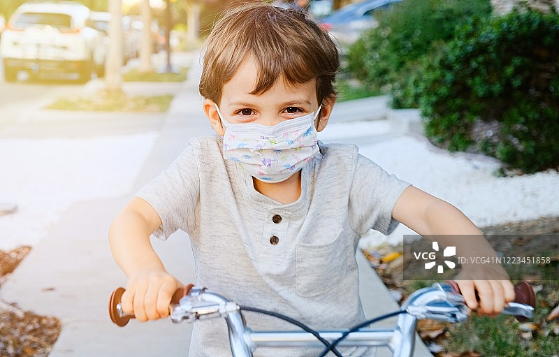 小男孩骑着自行车戴着防护面具图片素材