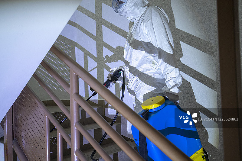 一名身着防护服的妇女正在为住宅楼空间消毒图片素材