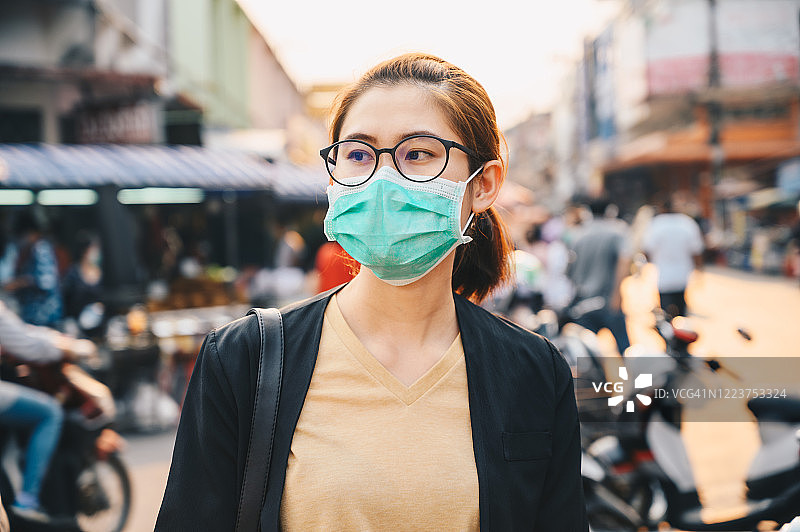 在大流行情况下戴口罩以保护空气污染或病毒的妇女。图片素材