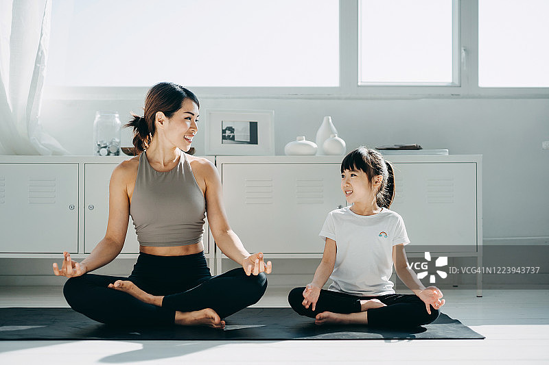 快乐的年轻亚洲母亲和小女儿一起锻炼和练习瑜伽在家里图片素材