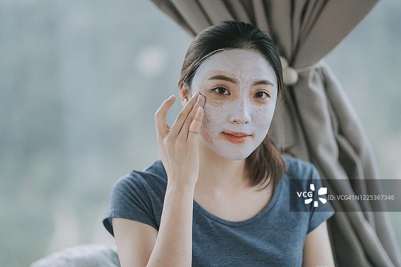 一位亚洲中国美女在卧室里用粘土面具玩得很开心图片素材