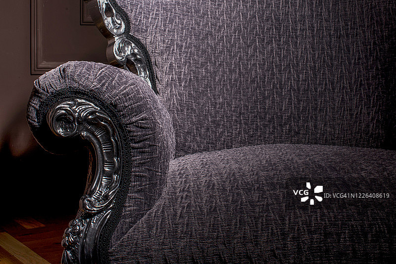 现代豪华扶手椅上的扶手细节与银色线条和紫色天鹅绒纺织品在深色背景与文字空间图片素材