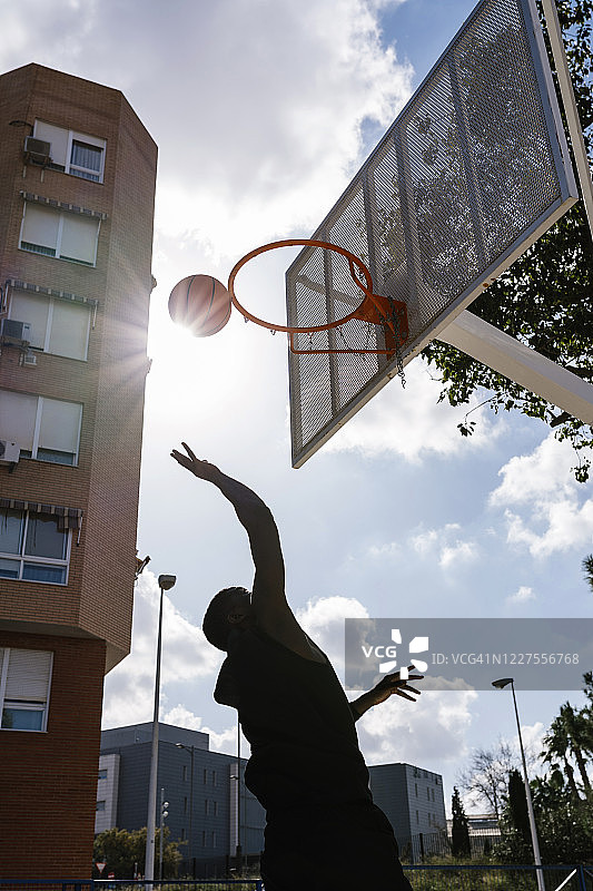 年轻人向太阳投掷篮球图片素材