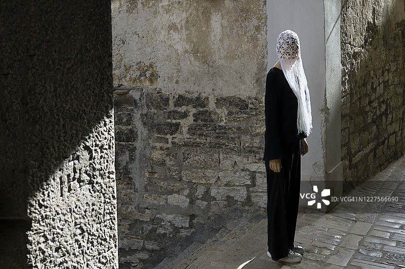克罗地亚罗温吉，一名身穿黑色衣服，头戴白色带流苏的钩针头饰的妇女图片素材