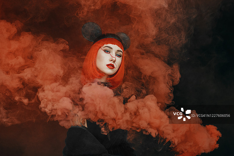 漂亮的时尚女孩的肖像与红色鲍勃发型和老鼠帽子在浓厚的红色烟雾图片素材