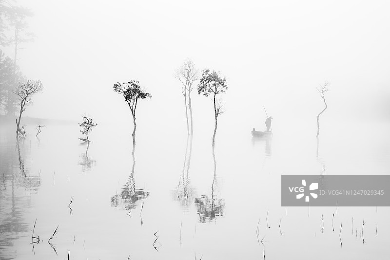 抽象的风景和孤独的渔民在湖上的单色摄影图片素材