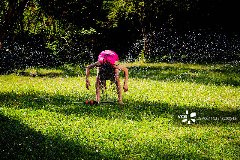 小女孩在玩花园里的洒水器图片素材